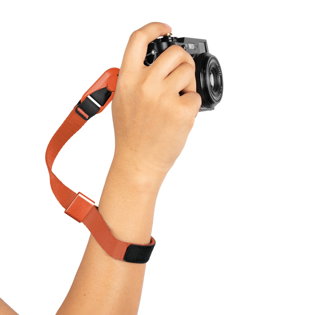 Hand holding a camera with an ibis color cuff on a white background Hand holding a camera with an ibis color cuff on a white background