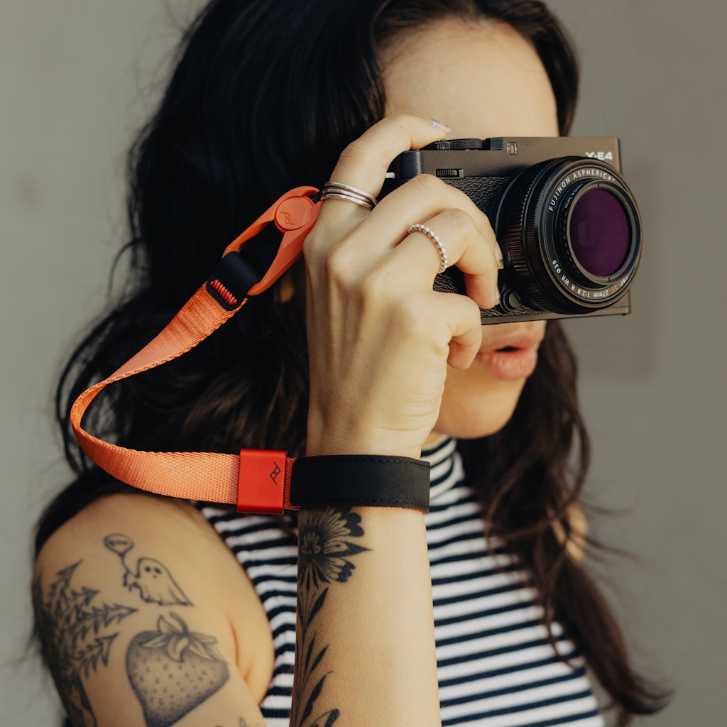 Person holding a camera with an ibis color cuff against a neutral background Person holding a camera with an ibis color cuff against a neutral background