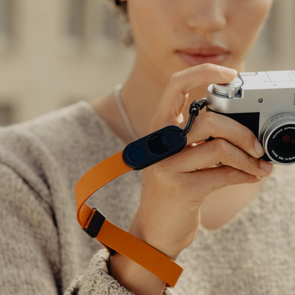 Person holding a camera with an Amber Leather Cuff, blurred background