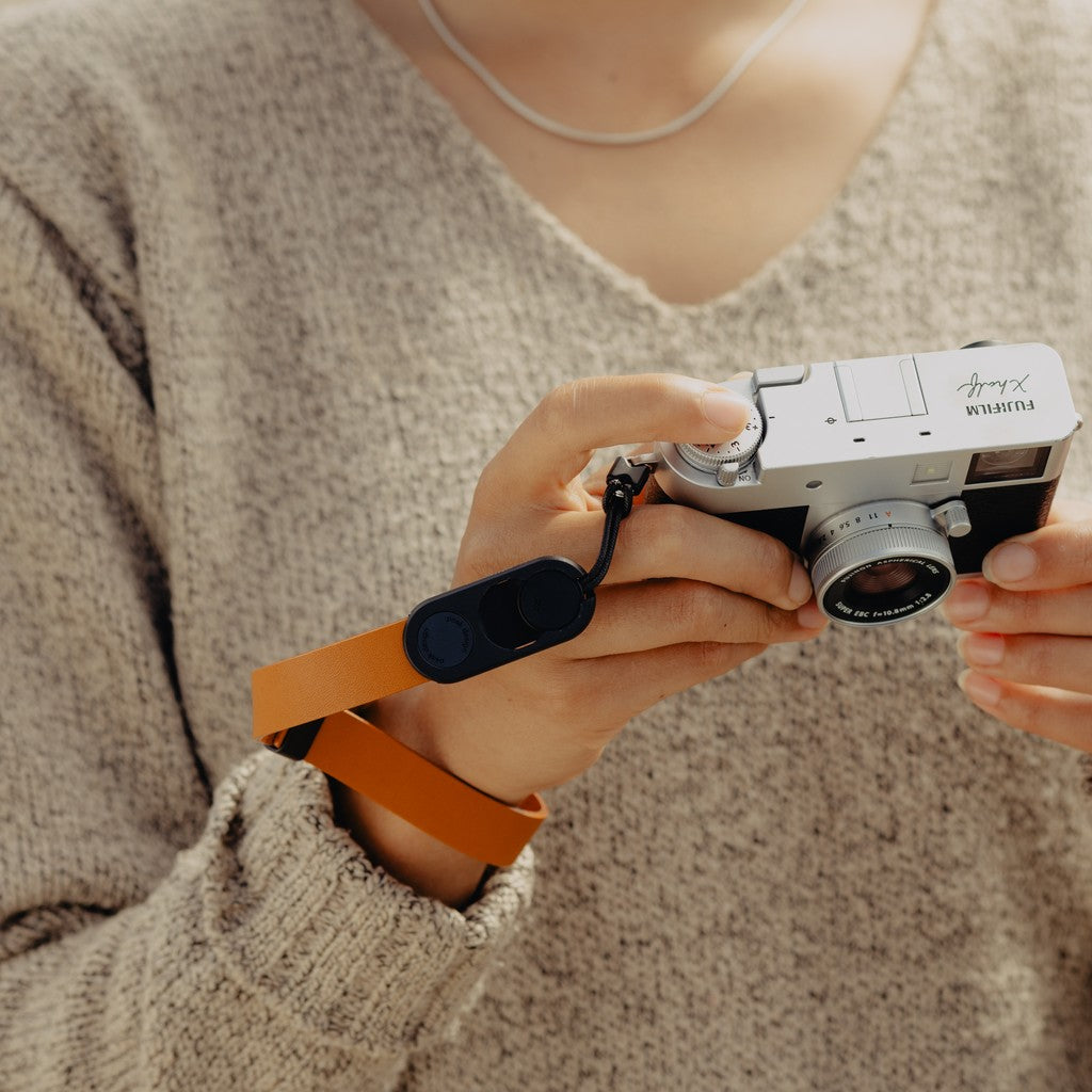 Person holding a camera attached to Amber Leather Cuff around their wrist Person holding a camera attached to Amber Leather Cuff around their wrist