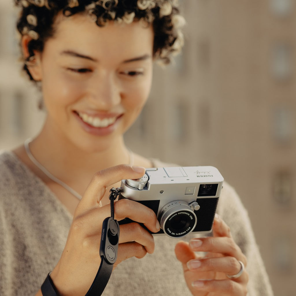 Person holding a camera attached to Black Leather Cuff with a blurred background Person holding a camera attached to Black Leather Cuff with a blurred background