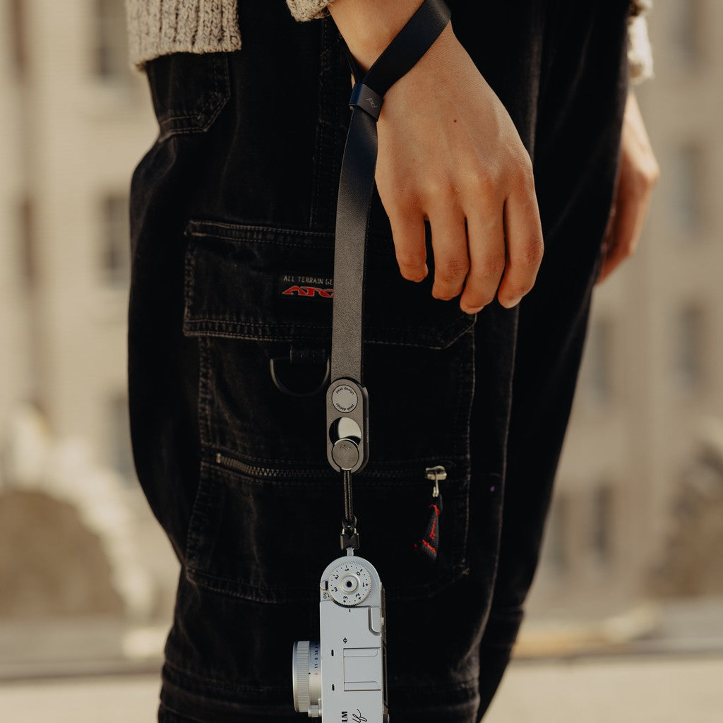 Person with a Black Leather Cuff on their wrist attached to a camera Person with a Black Leather Cuff on their wrist attached to a camera