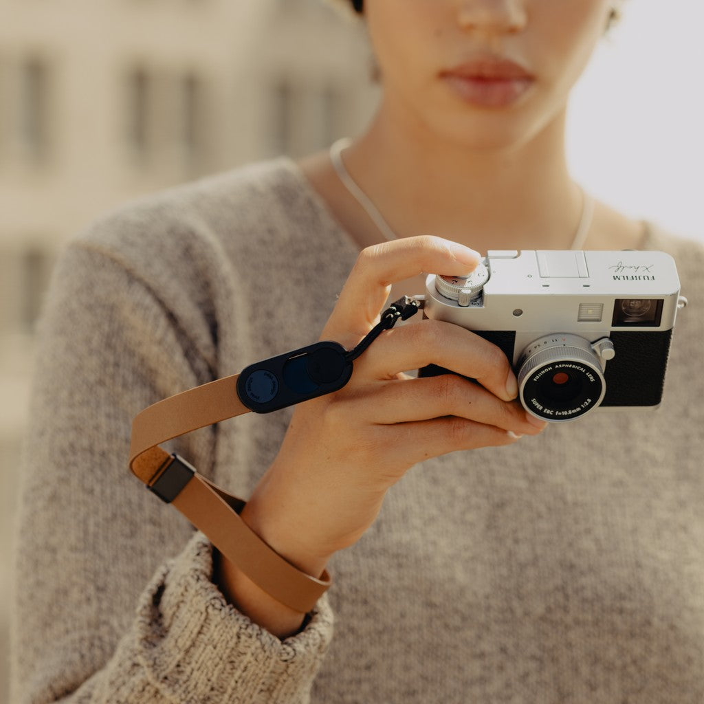 Person holding a camera attached to Tan Leather Cuff with a blurred background