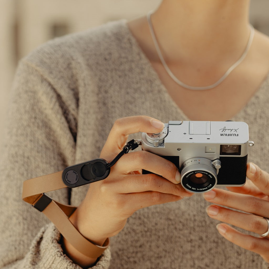 Person holding a camera with a Tan Leather Cuff, blurred background Person holding a camera with a Tan Leather Cuff, blurred background
